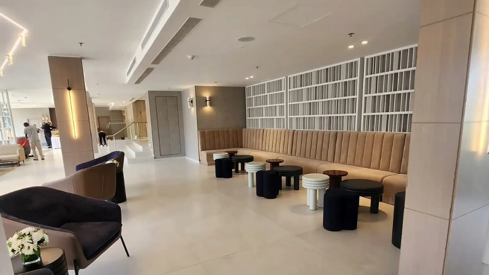 אותו לובי אחרי עבודות הגמר — תקרות גבס עם תאורה, ריצוף בהיר, בר וריהוט