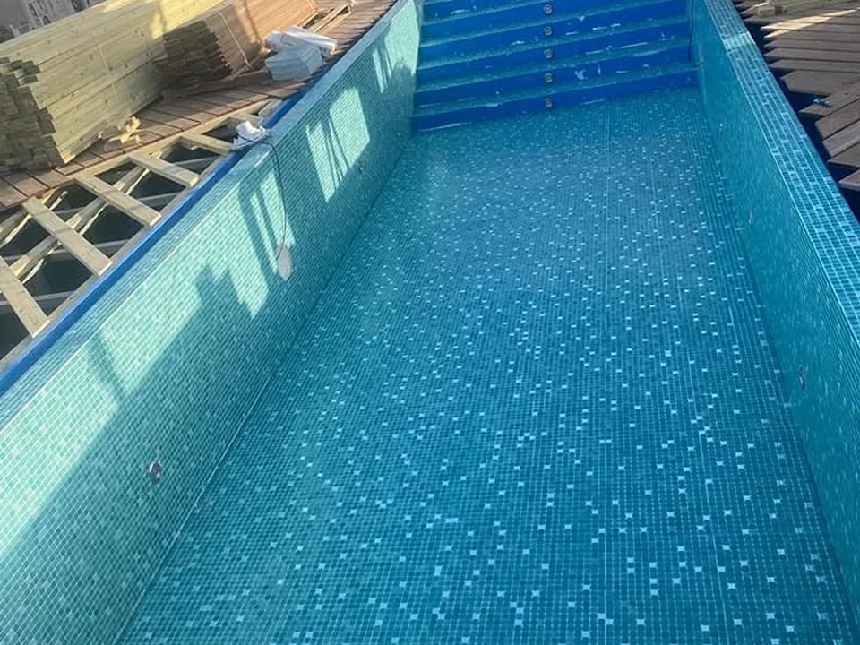 בריכה ארוכה עם חיפוי פסיפס כחול אחרי חידוש